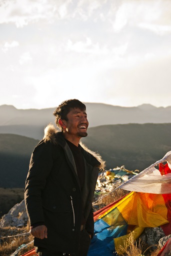 tibetan man smiling with tibet hills and mountains in background